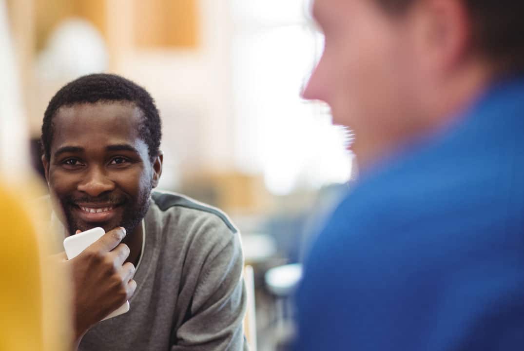 jeune homme souriant à l'écoute au sein d'un groupe de jeunes gens