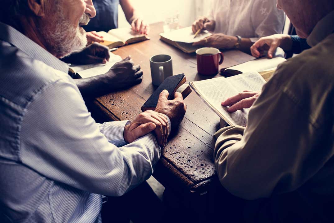 groupe échangeant autour d'un café, bibles en mains