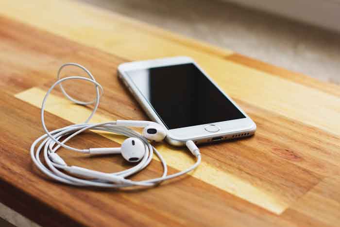 ressources-predication smartphone avec écouteurs posé sur une table en bois
